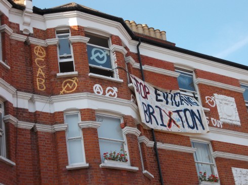 'Stop Evicting Brixton', ACAB, also 'we eat guardians' written down the side of a window
